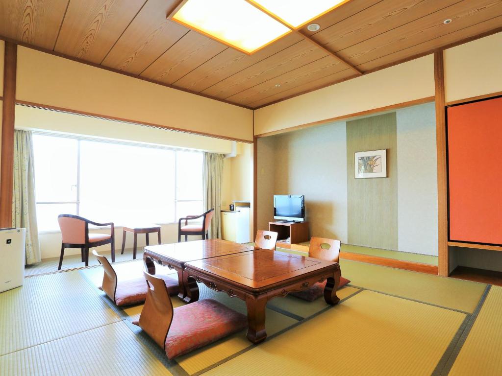 un salon avec une table et des chaises en bois dans l'établissement Bay Resort Hotel Shodoshima, à Shodoshima