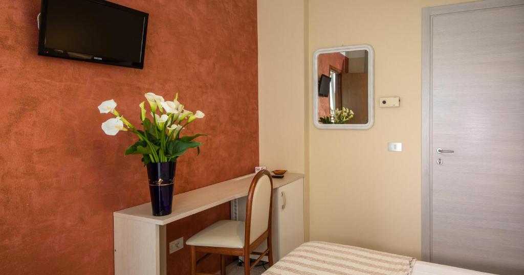 Cette chambre dispose d'un bureau avec un vase de fleurs. dans l'établissement Acapulco Beach, à Lido di Jesolo