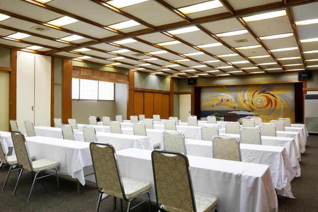 une salle de conférence avec des tables et des chaises blanches dans l'établissement Yoshidaya Sannoukaku, à Kaga 37 autres photos