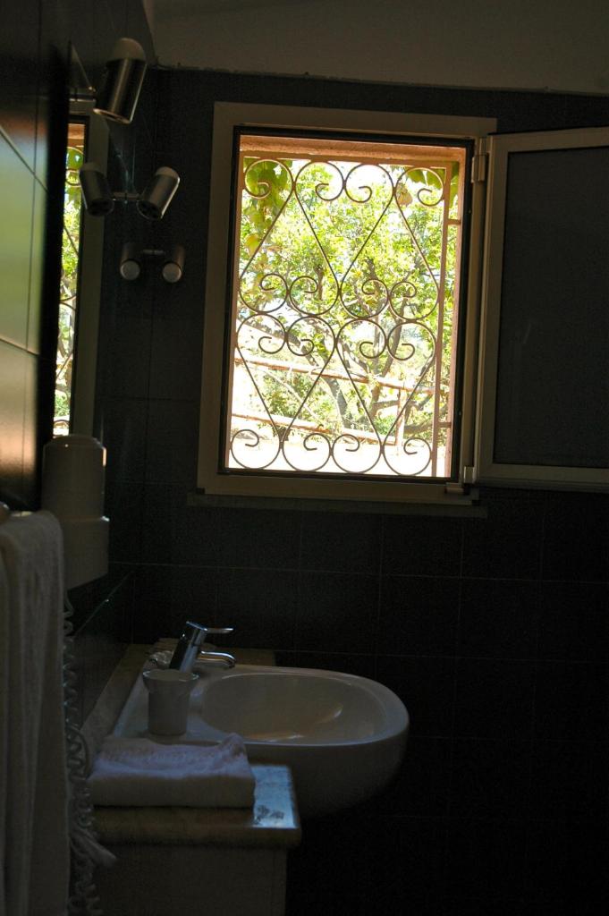 une salle de bain avec un lavabo et une fenêtre dans l'établissement Residence Fenicia, à Villasimius