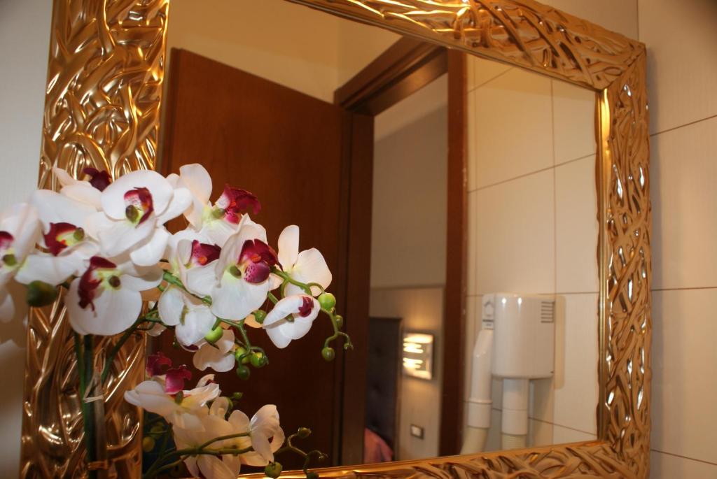 - un miroir avec un vase de fleurs dans la salle de bains dans l'établissement Hotel Michela, à Marina di Massa