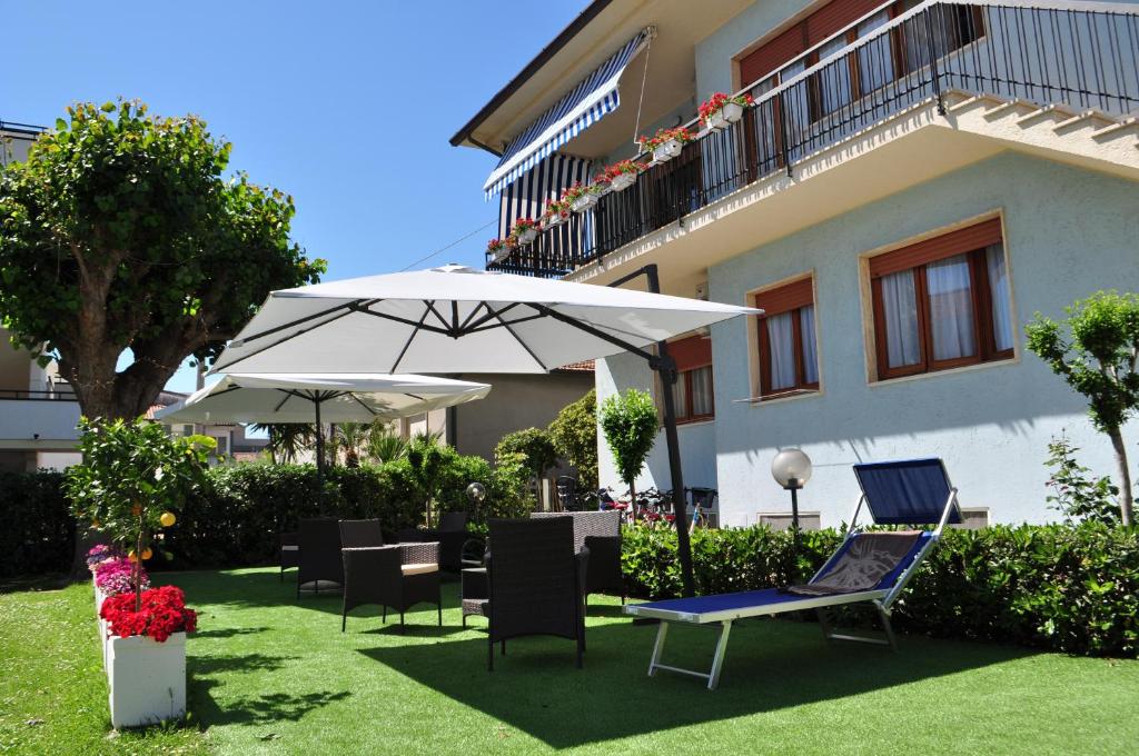 un patio avec des chaises et des parasols en face d'un bâtiment dans l'établissement Hotel Gianna, à Roseto degli Abruzzi