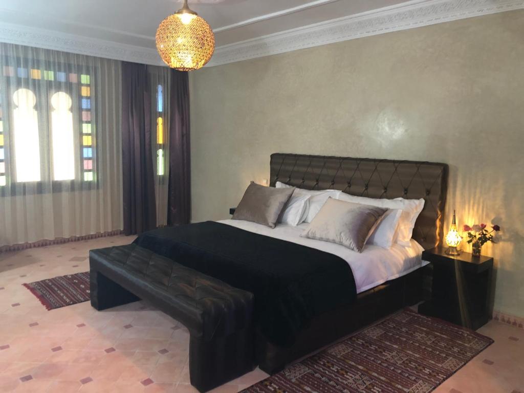 - une chambre avec un grand lit et un banc noir dans l'établissement Riad le Jasmin, à Taroudant