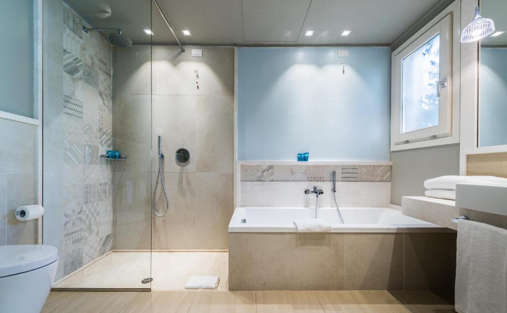 une salle de bain avec une douche, une baignoire et un lavabo dans l'établissement Forte Village Resort - Le Palme, à Santa Margherita di Pula