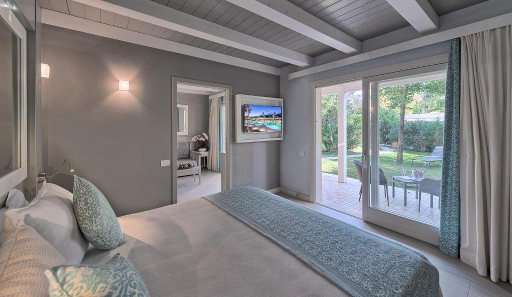 une chambre avec un lit et une porte coulissante en verre dans l'établissement Forte Village Resort - Le Palme, à Santa Margherita di Pula