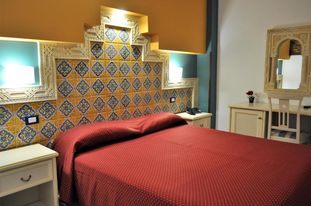 une chambre avec un lit rouge et un miroir dans l'établissement Al-Tair, à San Vito Lo Capo