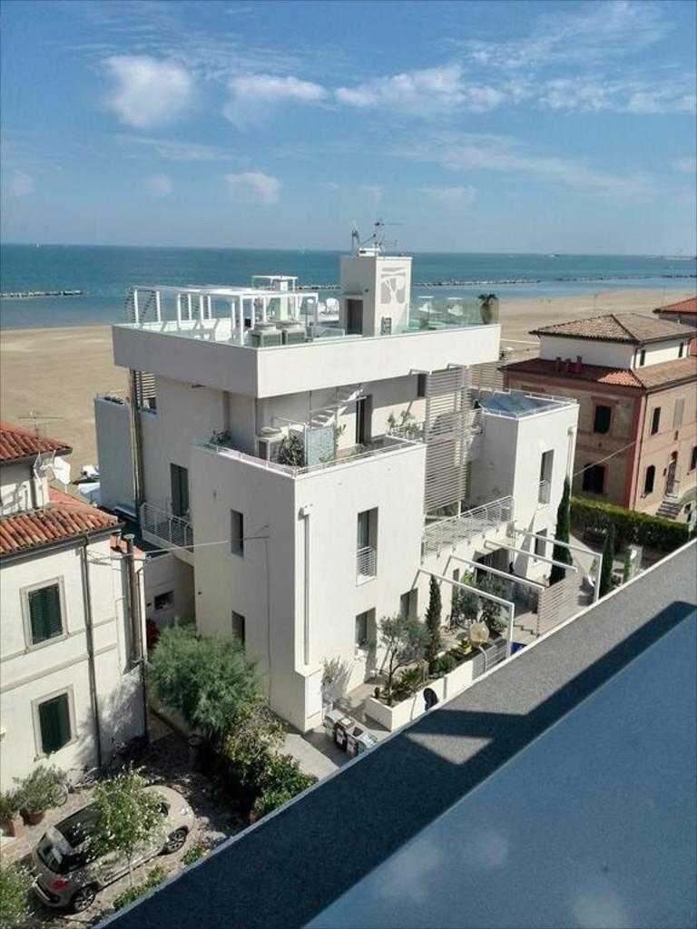 une vue d'un grand bâtiment blanc avec la plage dans l'établissement Hotel Madalù, à Rimini