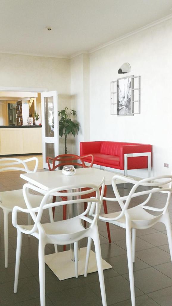un salon avec une table et des chaises blanches dans l'établissement Hotel Montmartre, à Rimini