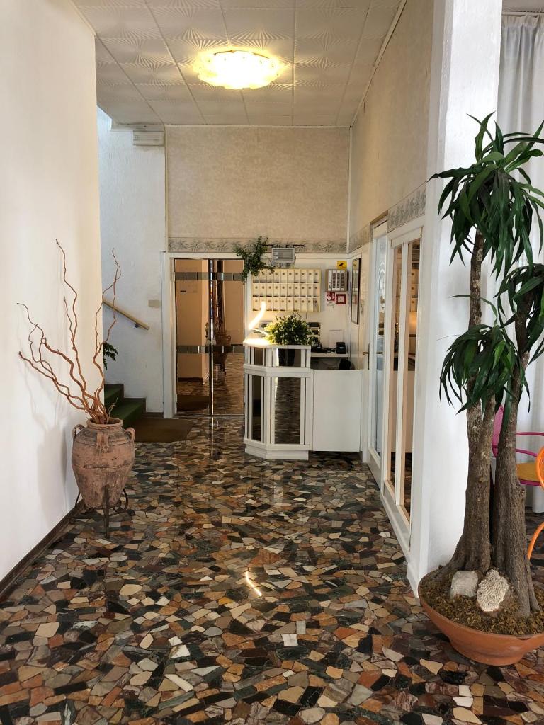 un couloir avec une chambre dotée d'un sol en pierre et de plantes dans l'établissement Hotel Marlisa Pier, à Lido di Jesolo