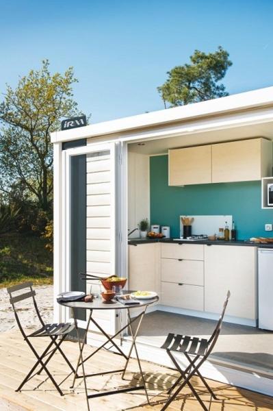 un patio avec une table et deux chaises ainsi qu'une cuisine dans l'établissement Camping Le Bois Verdon, à Saint-Jean-de-Monts