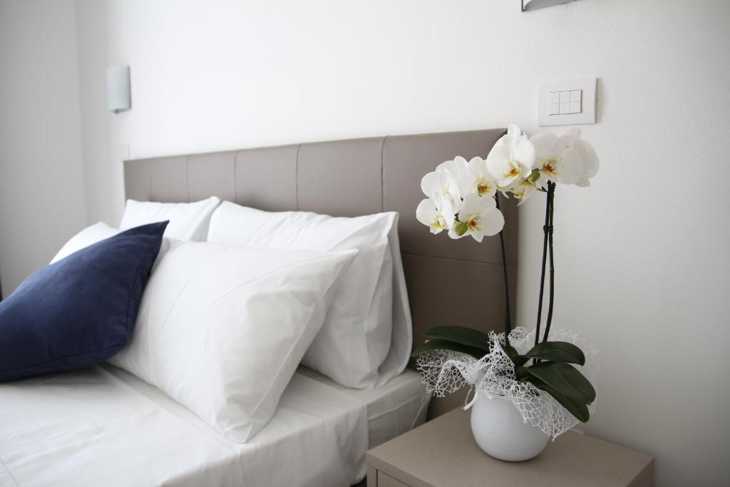 un lit avec des oreillers blancs et un vase avec des fleurs dans l'établissement Hotel Arena, à Lido di Jesolo
