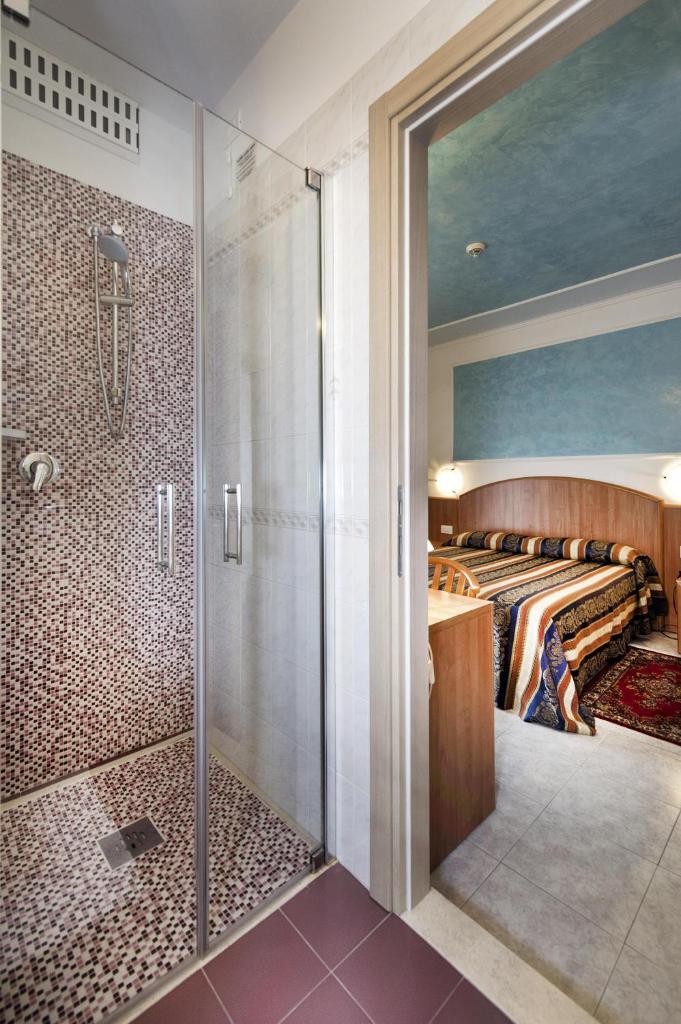 une salle de bain principale avec douche et un lit dans l'établissement Hotel Hollywood***S, à Lido di Jesolo