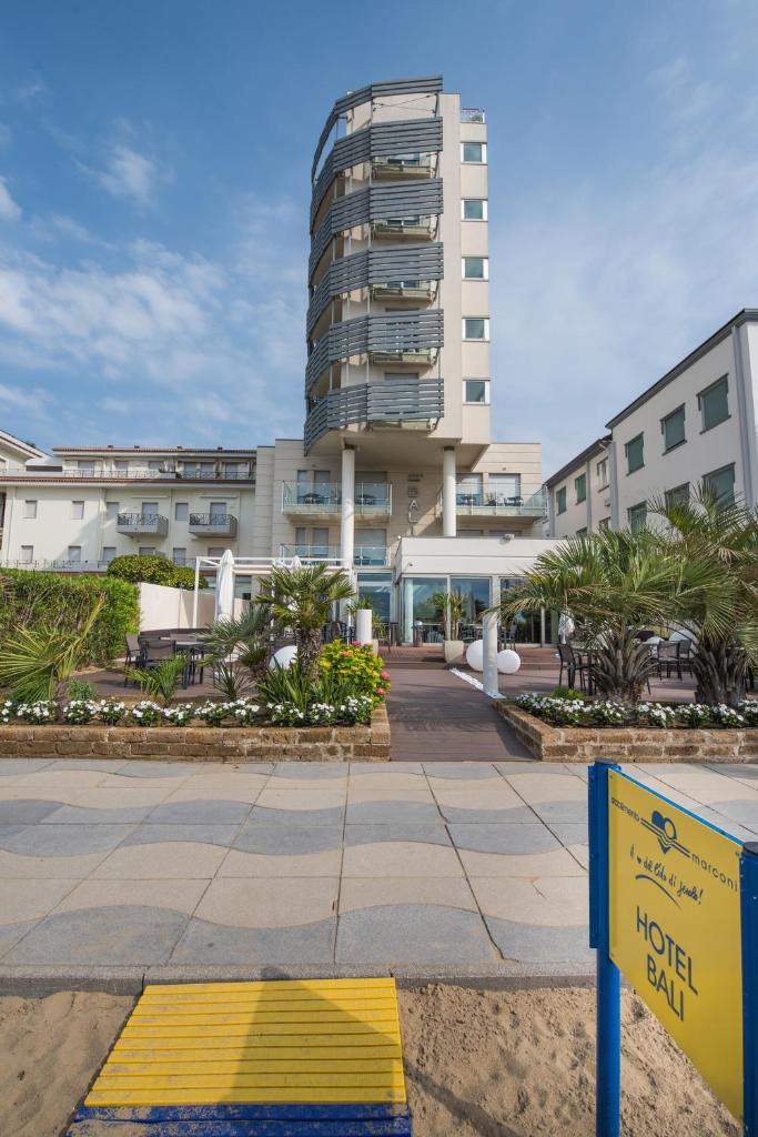 un bâtiment d'hôtel avec un panneau jaune devant lui dans l'établissement Boutique Hotel Bali, à Lido di Jesolo