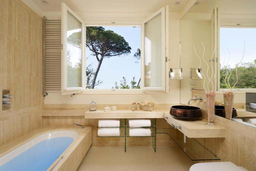 une salle de bain avec une baignoire, une fenêtre et un arbre dans l'établissement Villa Roma Imperiale, à Forte dei Marmi