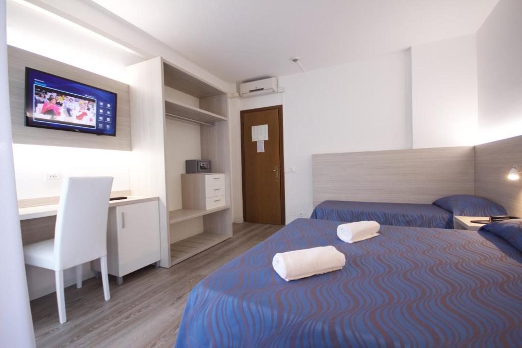 une chambre avec deux lits, un bureau et une télévision dans l'établissement Hotel Serenella, à Lido di Jesolo
