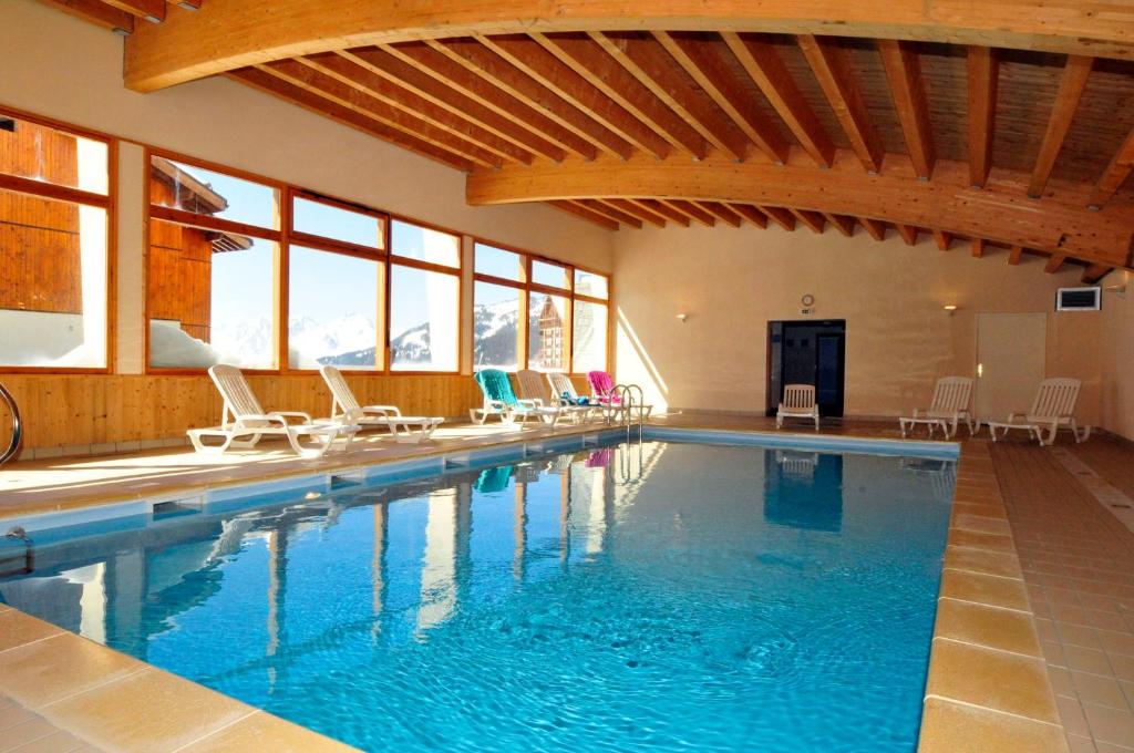 une grande piscine avec des chaises dans un bâtiment dans l'établissement Résidence Goélia Les 4 Vallées, à Saint-François-Longchamp