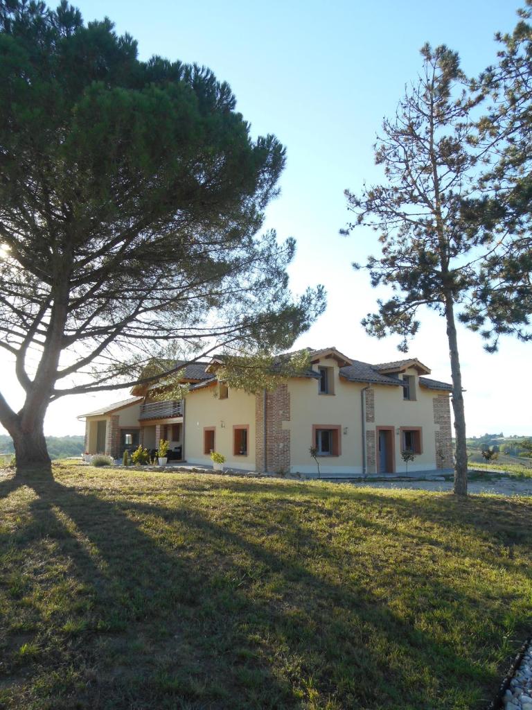 une maison sur une colline avec des arbres au premier plan dans l'établissement Gîtes Dans une Maison d'hôtes "Lieu Dit Cruzel", à Moissac