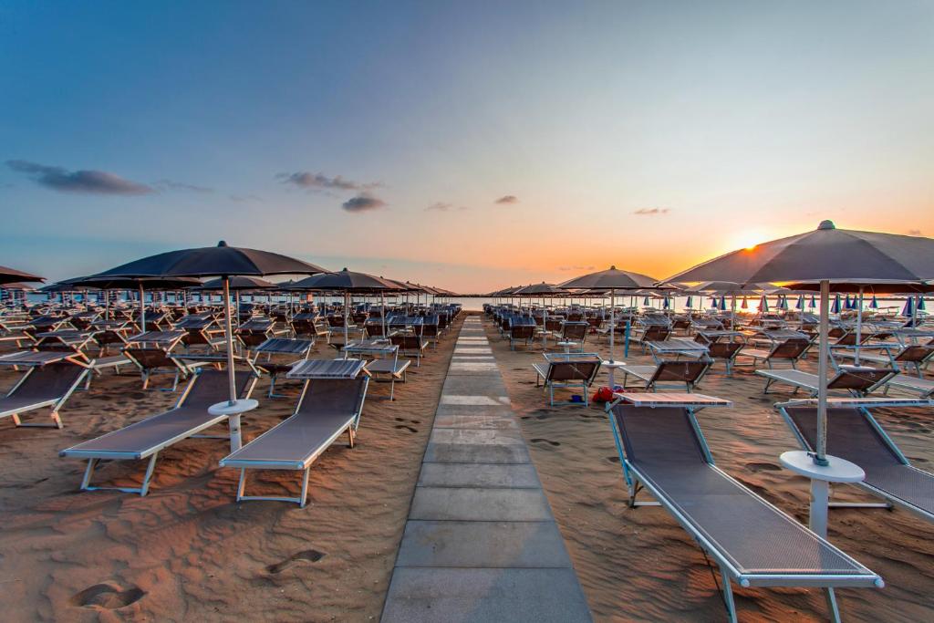 - une rangée de chaises sur une plage au coucher du soleil dans l'établissement Hotel Valverde & Residenza, à Cesenatico
