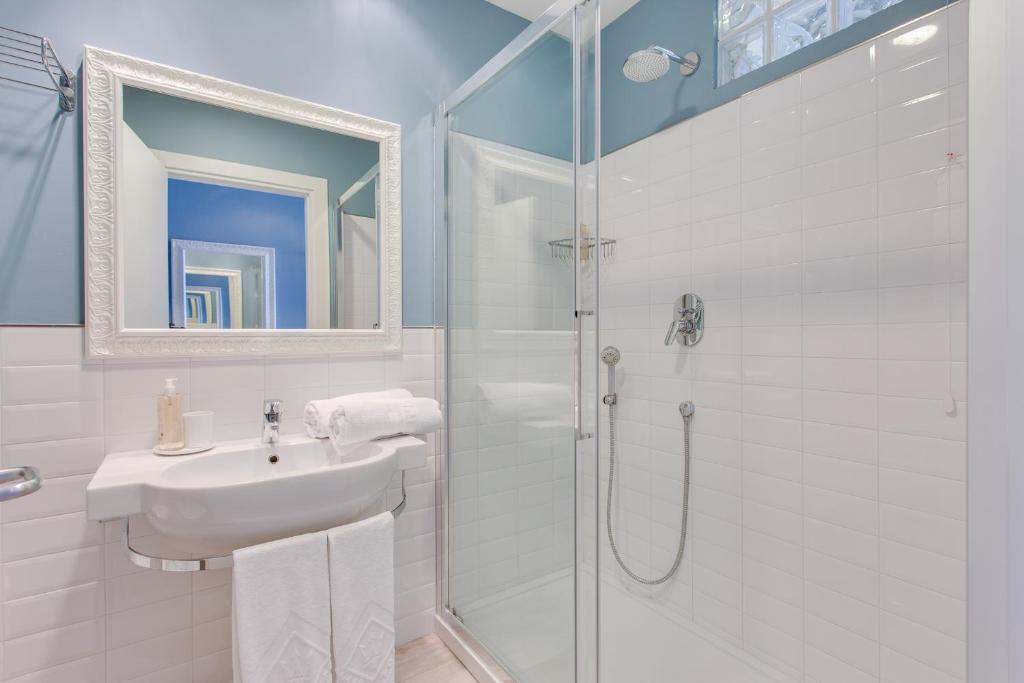 une salle de bain blanche avec lavabo et douche dans l'établissement Hotel Nettuno, à Cesenatico