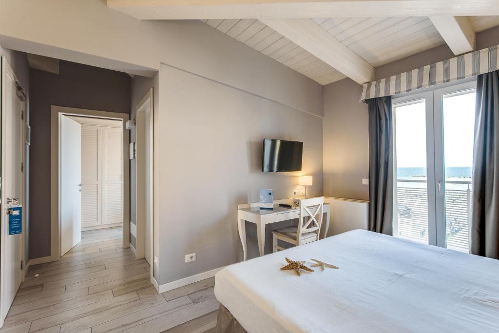 une chambre avec un lit et un bureau avec une télévision dans l'établissement Hotel Nettuno, à Cesenatico
