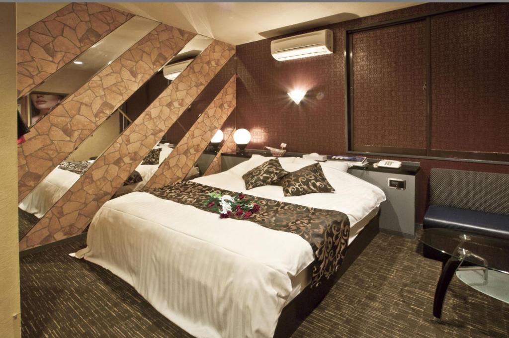 une chambre d'hôtel avec un grand lit et une chaise dans l'établissement Hotel Hanabi (Love Hotel), à Chikugo