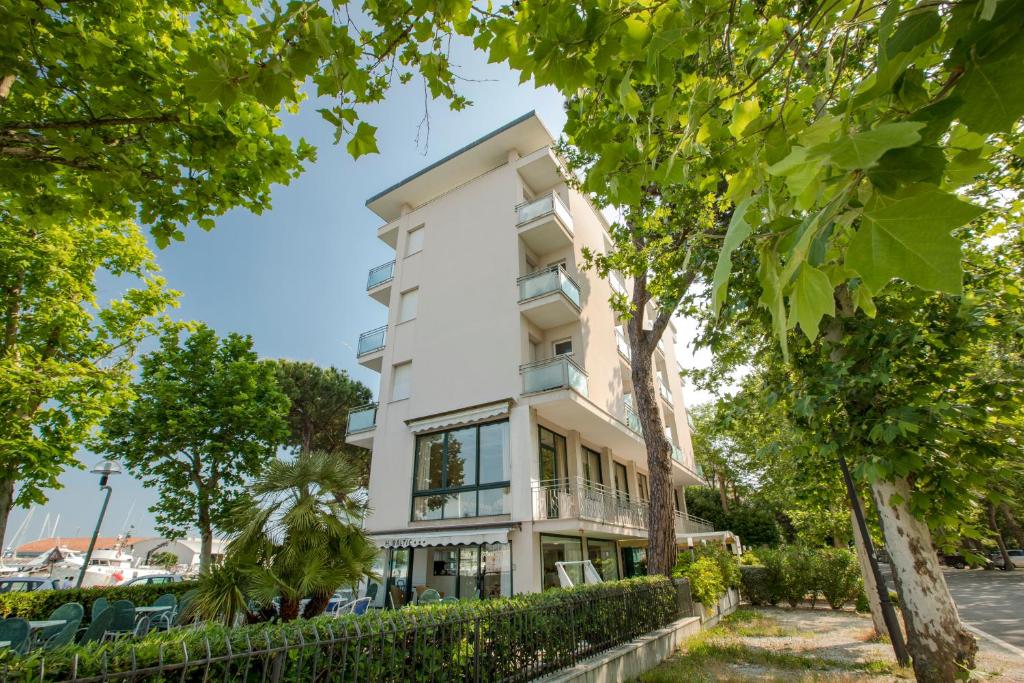 un bâtiment blanc avec des arbres devant dans l'établissement Hotel Baltic, à Cesenatico