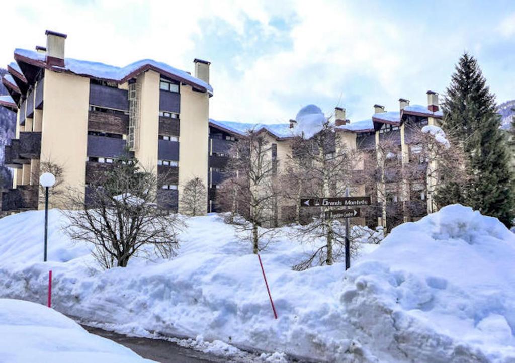 un grand bâtiment avec de la neige devant lui dans l'établissement Residence Grand Roc - Kercham, à Chamonix-Mont-Blanc