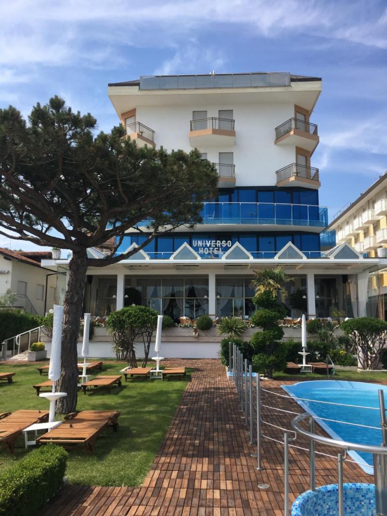 un hôtel avec une piscine et un bâtiment dans l'établissement Hotel Universo, à Lido di Jesolo