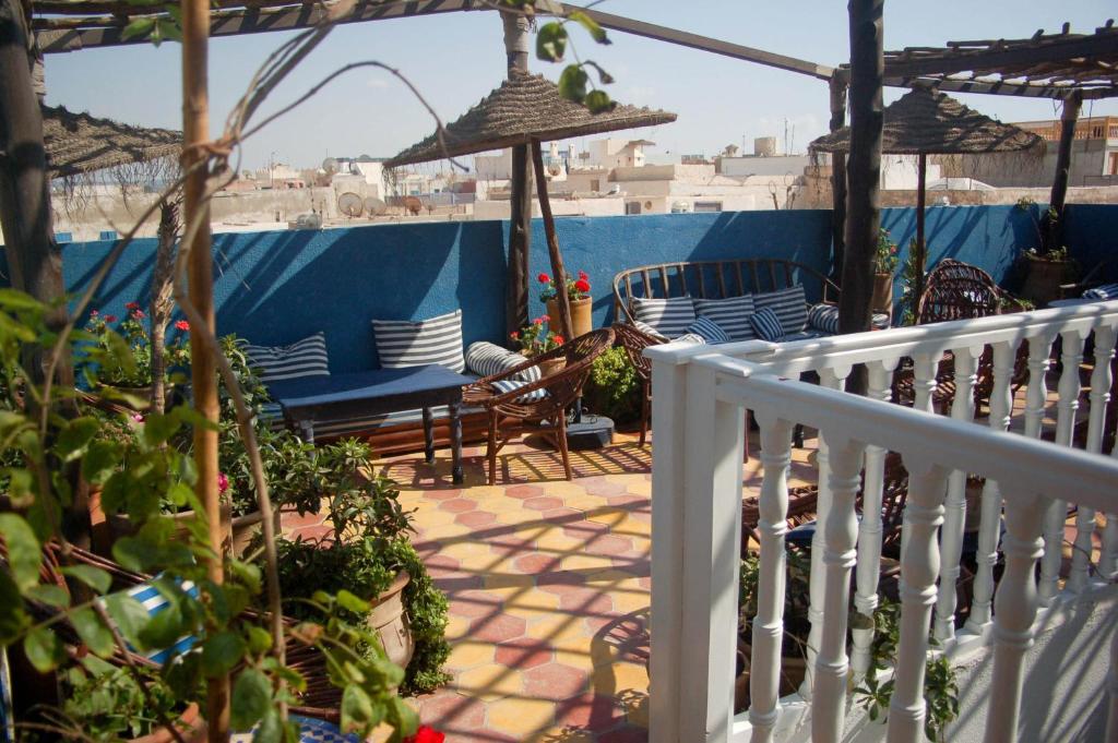 un balcon avec des chaises, des tables et des parasols dans l'établissement Riad Le Grand Large, à Essaouira
