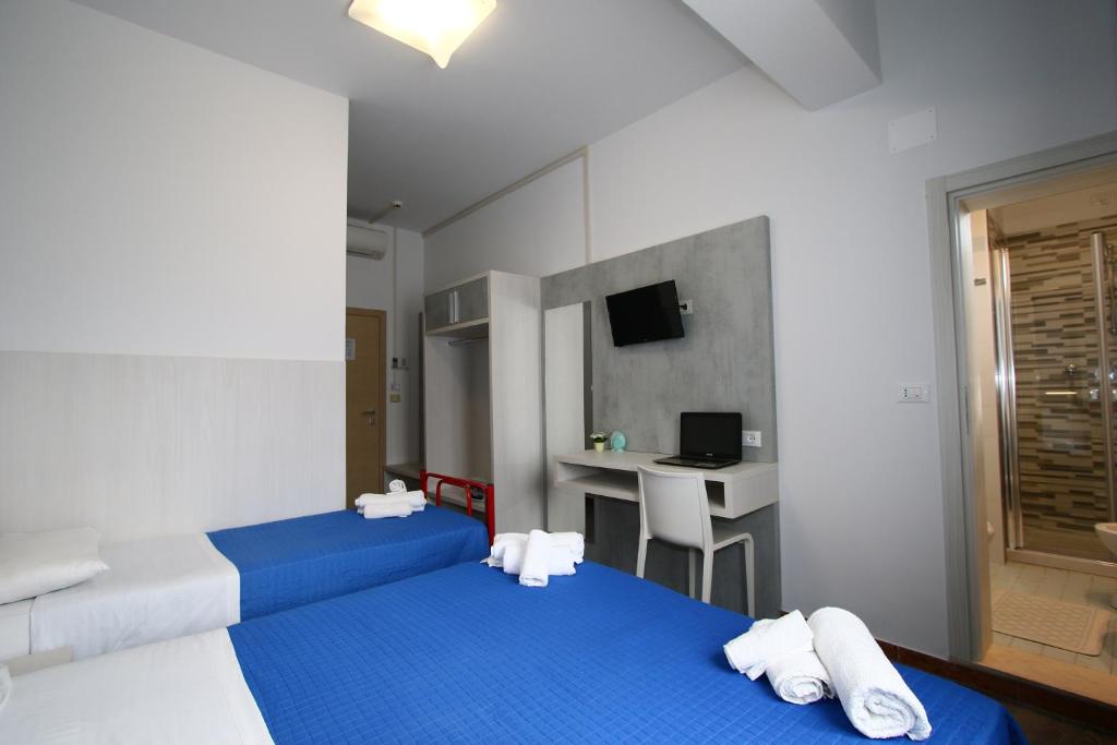 une chambre d'hôtel avec deux lits et un bureau dans l'établissement Hotel Kim, à Rimini