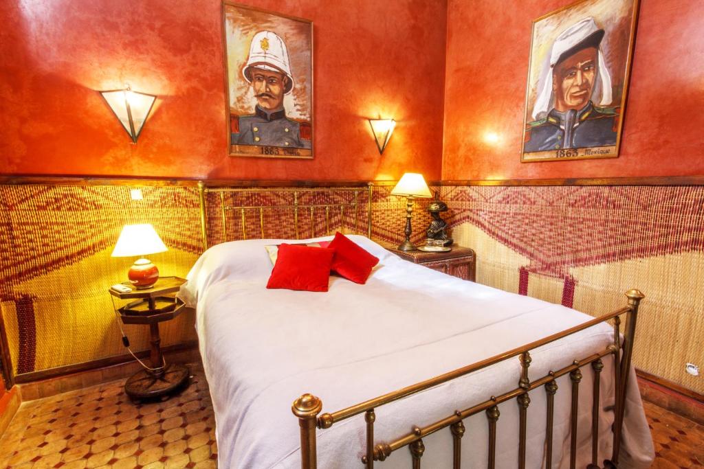 - une chambre avec un lit et deux portraits sur le mur dans l'établissement Riad El Arsat & Spa, à Marrakech
