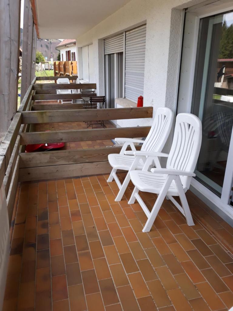 2 chaises blanches assises sur la terrasse couverte d'un bâtiment dans l'établissement Résidence le Faucon - Col du Donon, à Grandfontaine 8 autres photos