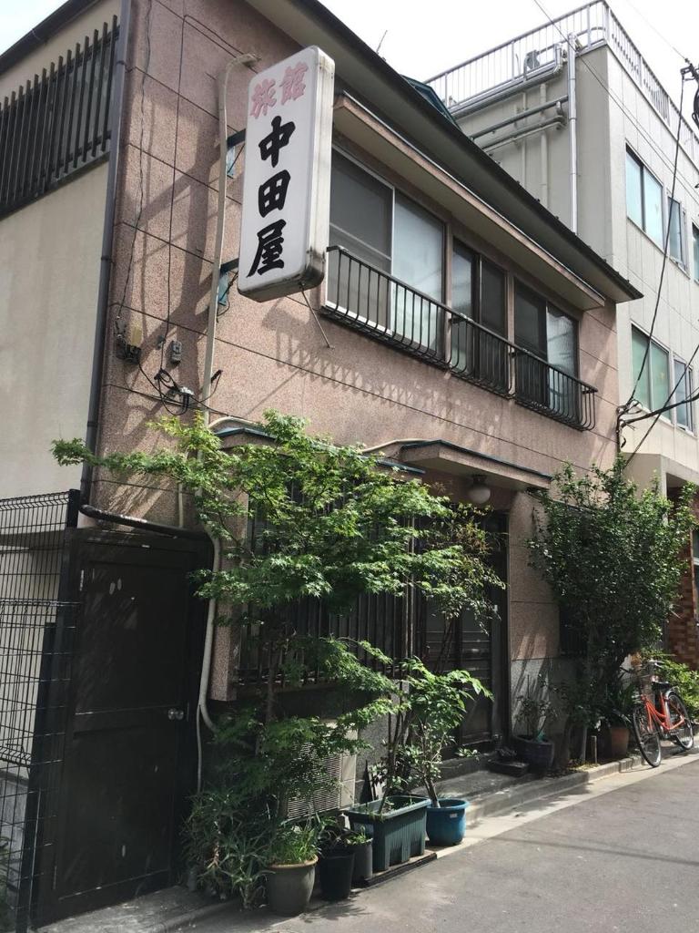 un bâtiment avec une enseigne sur le côté dans l'établissement Ryokan Nakadaya, à Tokyo