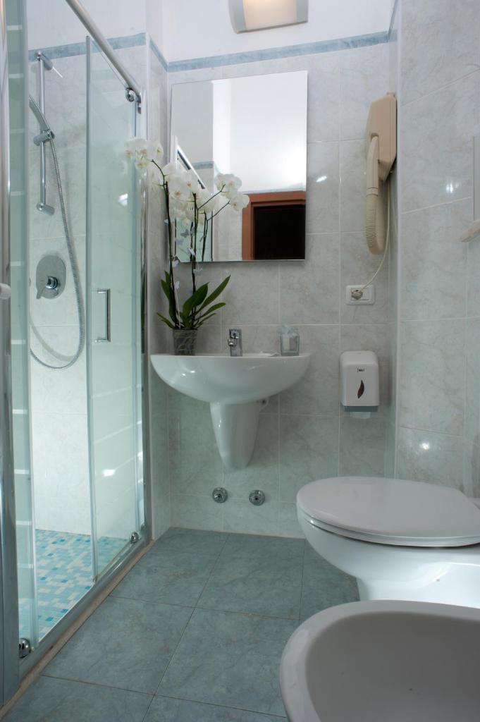 une salle de bain avec un lavabo, des toilettes et une douche dans l'établissement Hotel Alsen, à Rimini