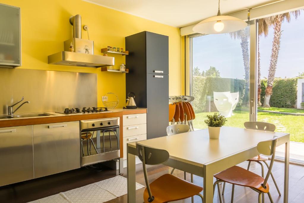 une cuisine avec des murs jaunes et une table avec des chaises dans l'établissement Villa Oras, à Mascali