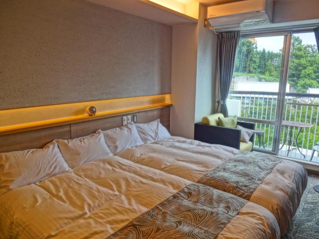une chambre d'hôtel avec un lit et un balcon dans l'établissement Hotel Spax Kusatsu, à Kusatsu