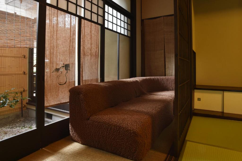 un salon avec une chaise et une fenêtre dans l'établissement Yadoya Nishijinso, à Kyoto