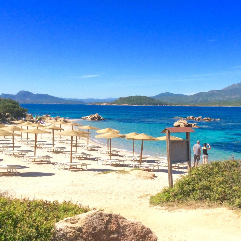 - une plage avec des parasols et des chaises et l'océan dans l'établissement Hotel Capriccioli, à Porto Cervo