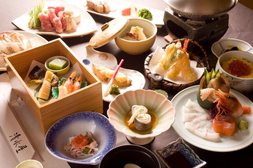 une table avec de nombreuses assiettes de nourriture dessus dans l'établissement Oyado Kiyomizuya, à Noboribetsu