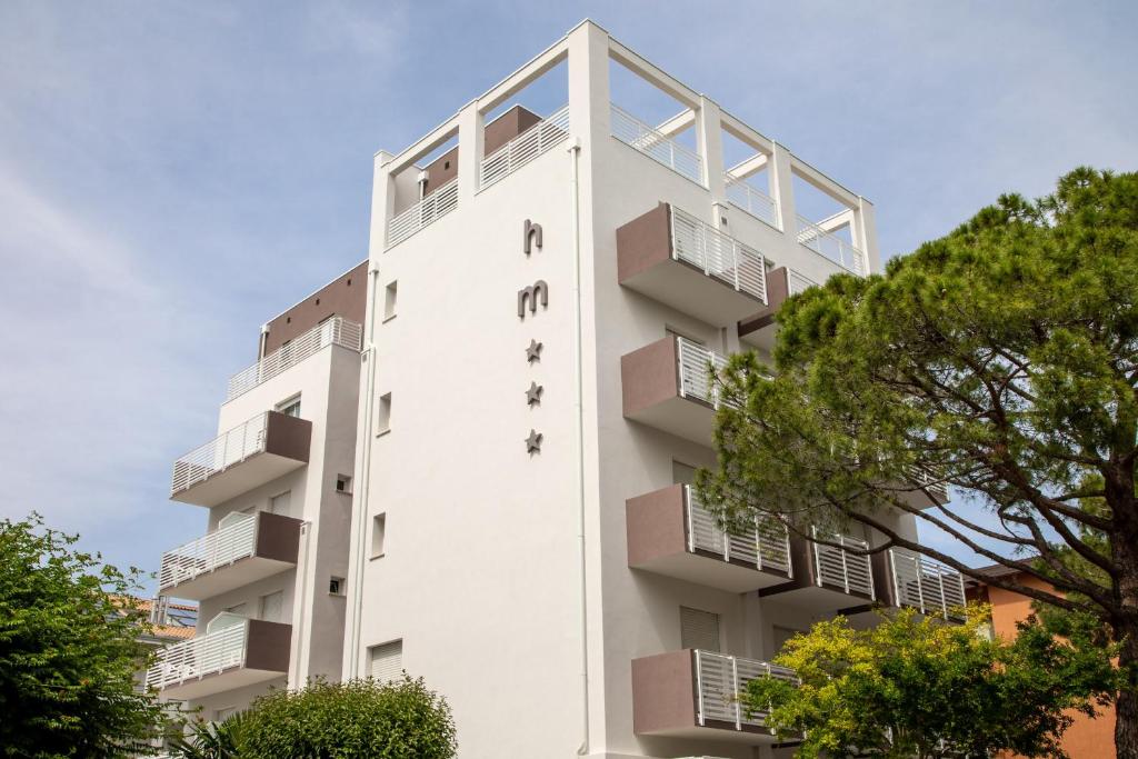 un immeuble blanc avec des balcons et des arbres dans l'établissement Hotel Mayer, à Lido di Jesolo