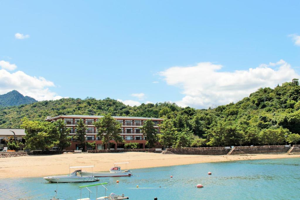 un hôtel sur une plage avec un bateau dans l'eau dans l'établissement Miyajima Seaside Hotel, à Miyajima