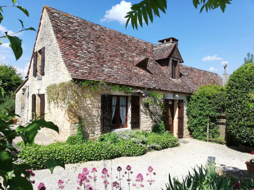 une vieille maison en pierre avec des fleurs devant dans l'établissement La Ferme de l'Embellie Gîtes et Chambres d'Hôtes, au Buisson de Cadouin
