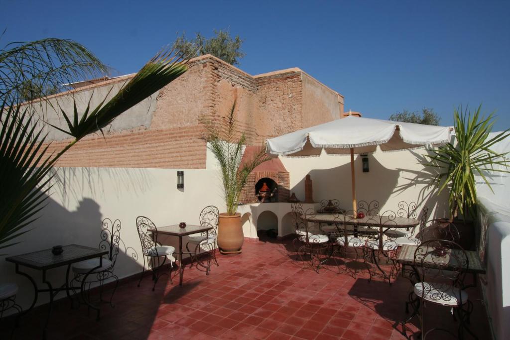 un patio avec tables, chaises et un parasol dans l'établissement Riad Morgane, à Marrakech