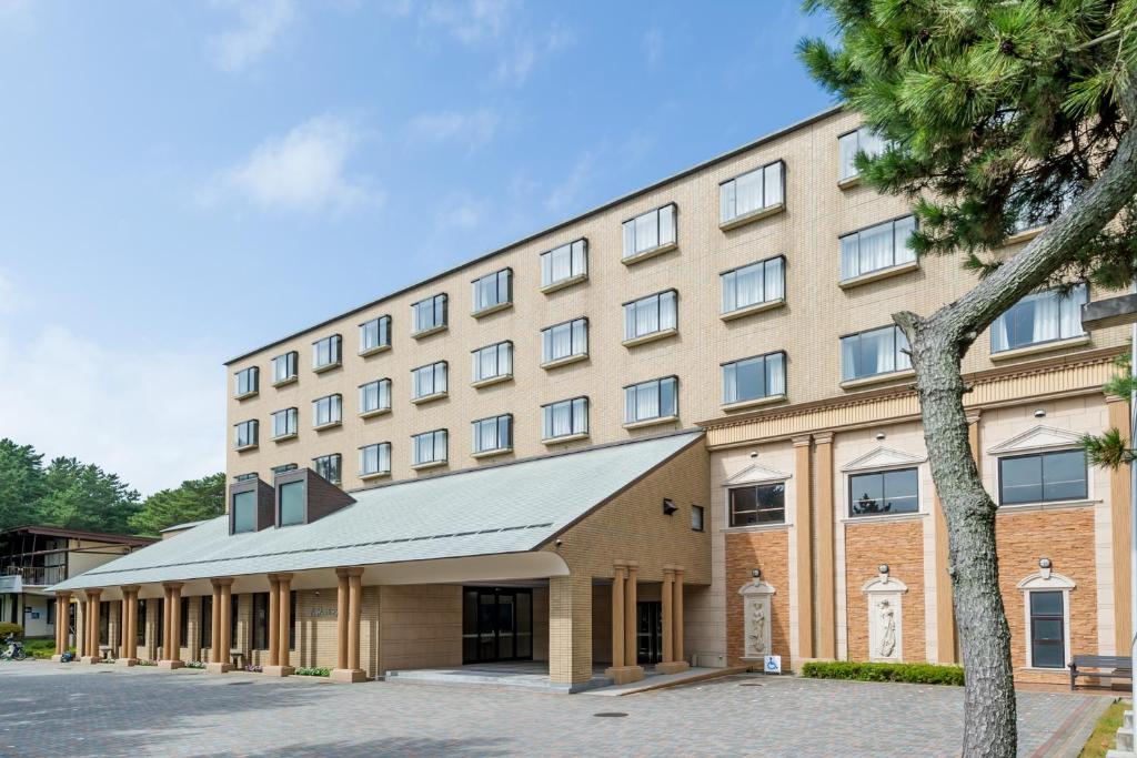 un grand bâtiment avec un palmier devant dans l'établissement Oarai Park Hotel, à Ōarai