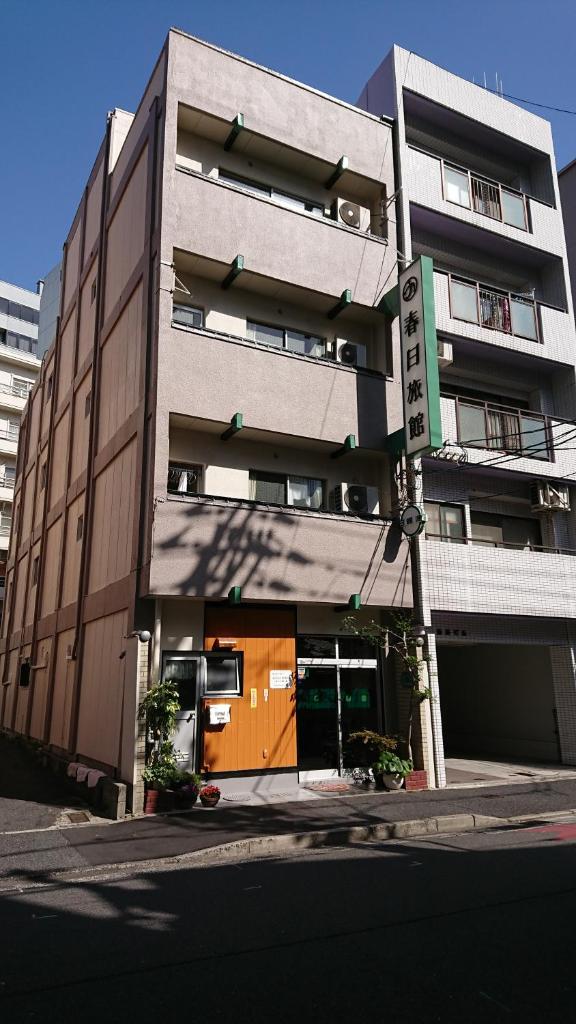 un bâtiment avec une porte orange devant lui dans l'établissement Kasuga Ryokan, à Hiroshima
