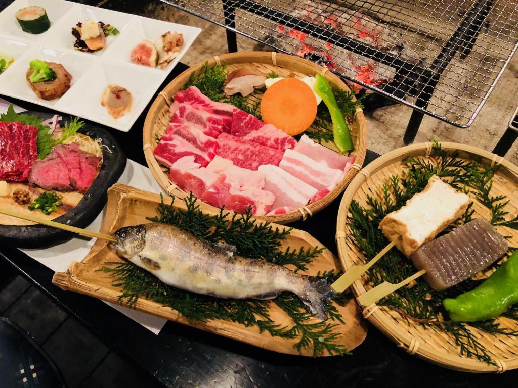 une table garnie d'assiettes de nourriture avec de la viande et des légumes dans l'établissement Ryokan Yamanoyu, à Minamioguni