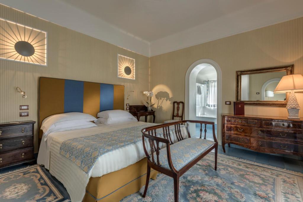une chambre avec un lit, une chaise et un miroir dans l'établissement Augustus Hotel & Resort, à Forte dei Marmi