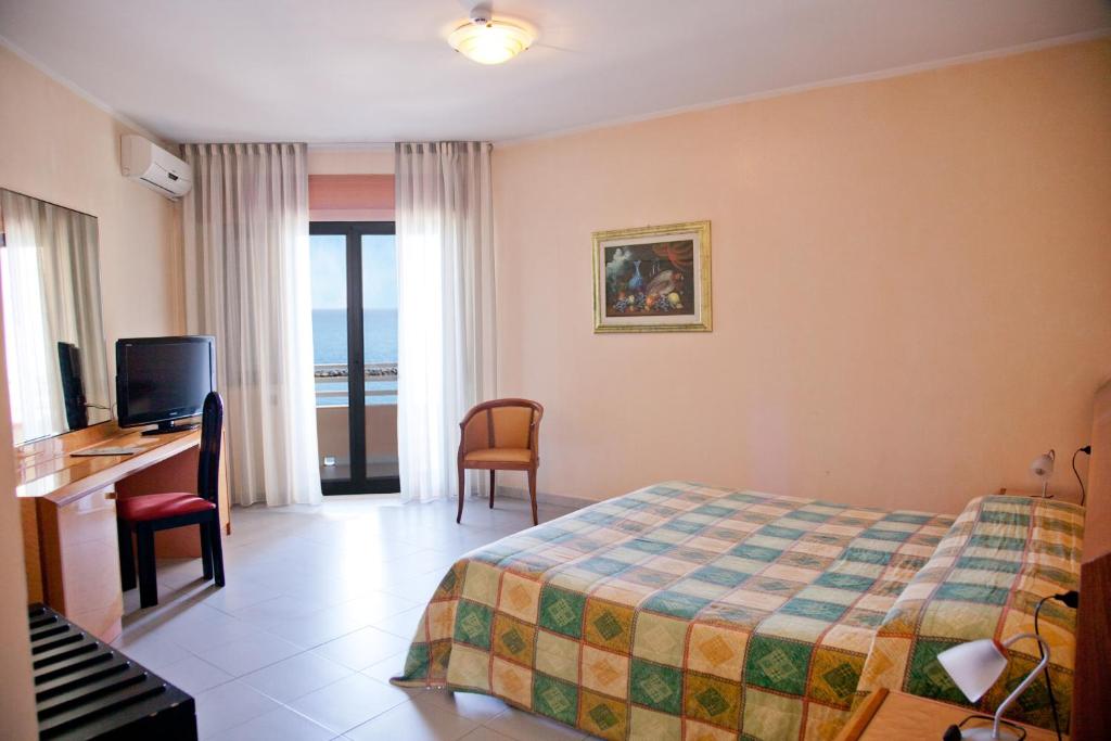 une chambre d'hôtel avec un lit, un bureau et une télévision dans l'établissement Hotel Melissa, à Torre Melissa