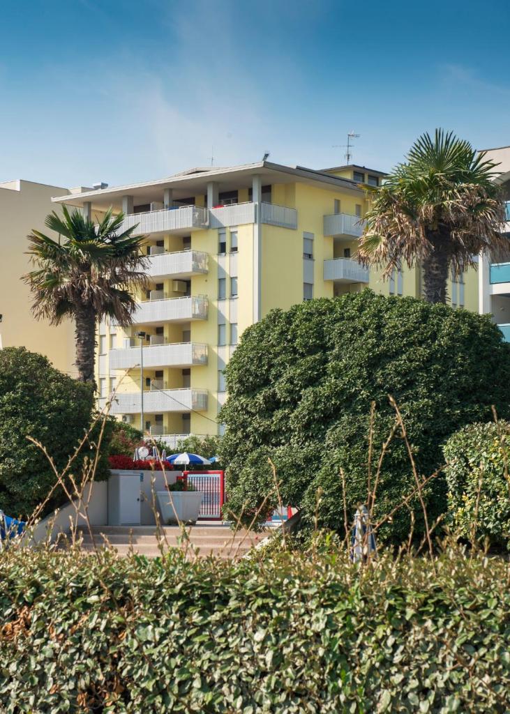 un grand bâtiment avec des palmiers devant dans l'établissement Appartamenti Aurora, à Bibione