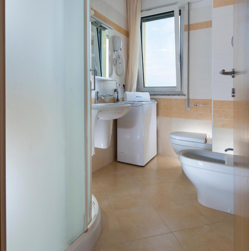 une salle de bain avec toilettes, lavabo et miroir dans l'établissement Appartamenti Aurora, à Bibione